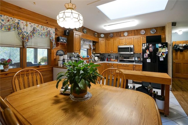 dining area with a skylight, wooden walls, and light tile patterned floors