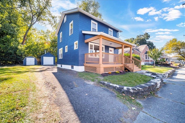 view of front of home with a garage, covered porch, a shed, and a front yard