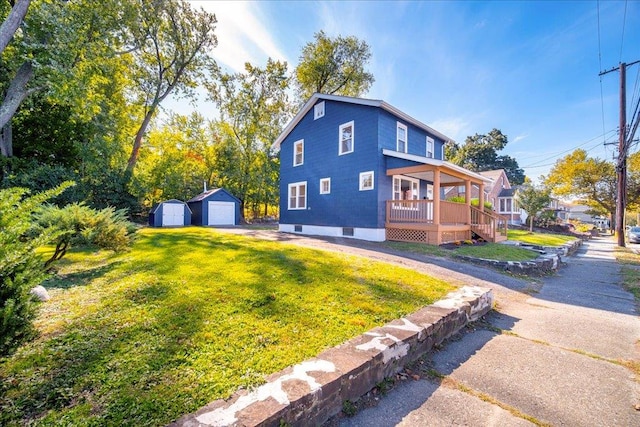 view of side of home with a yard, an outbuilding, covered porch, and a garage