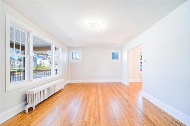 spare room featuring radiator and light hardwood / wood-style flooring