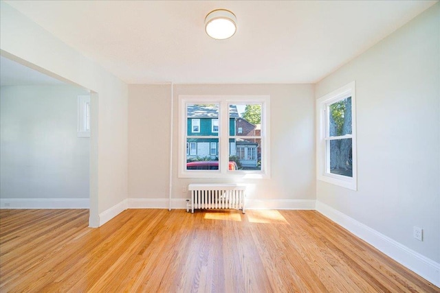 empty room featuring radiator heating unit and light wood-type flooring