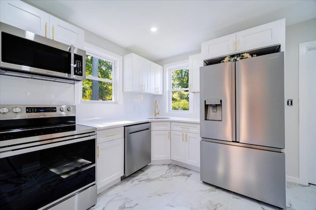 kitchen with decorative backsplash, stainless steel appliances, white cabinetry, and sink