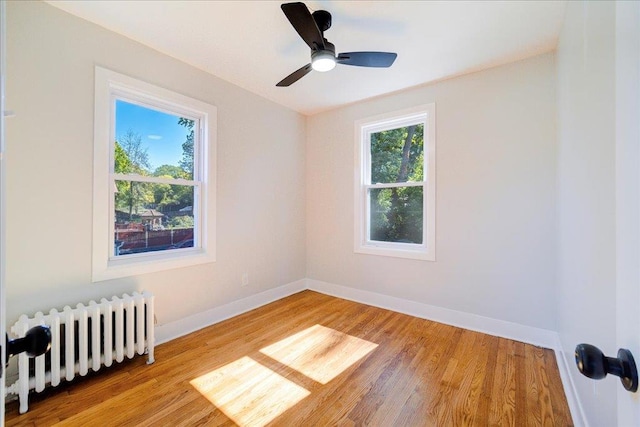 empty room with radiator heating unit, light hardwood / wood-style flooring, and ceiling fan