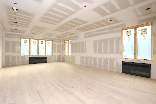 unfurnished living room with a wealth of natural light, radiator heating unit, and hardwood / wood-style flooring