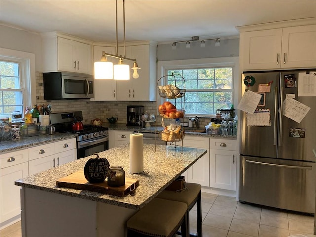 kitchen with a wealth of natural light, white cabinetry, and appliances with stainless steel finishes