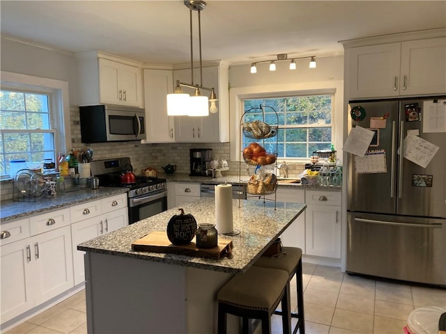 kitchen featuring white cabinetry, light stone countertops, a kitchen island, and stainless steel appliances