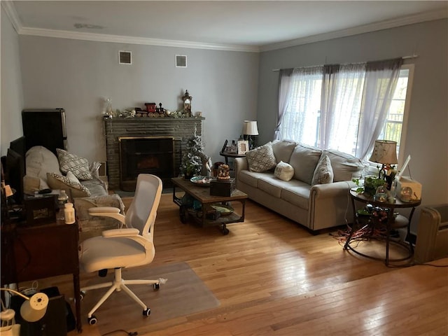 living room featuring a stone fireplace, light hardwood / wood-style floors, and ornamental molding