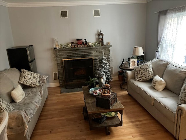 living room featuring a fireplace, light hardwood / wood-style flooring, and ornamental molding