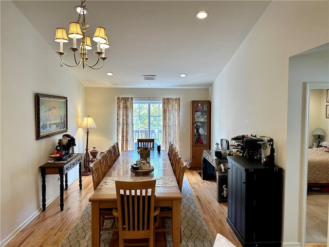 dining room with light hardwood / wood-style floors and a notable chandelier