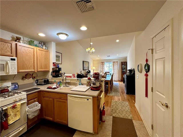 kitchen featuring kitchen peninsula, light wood-type flooring, white appliances, sink, and hanging light fixtures