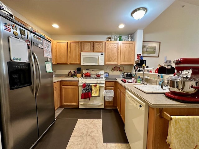 kitchen with kitchen peninsula, white appliances, dark tile patterned flooring, and sink