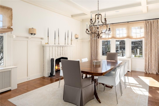 dining area featuring wood-type flooring, radiator, and beam ceiling