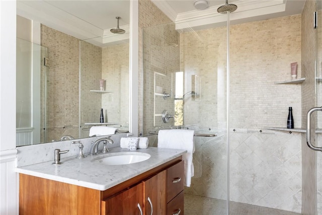 bathroom with a shower with door, vanity, and ornamental molding