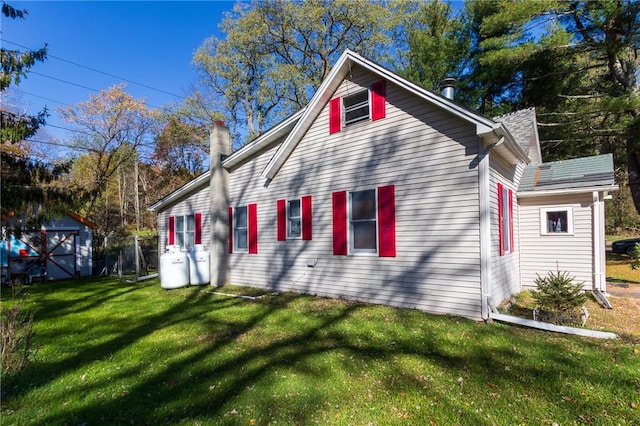 rear view of property featuring a shed and a yard