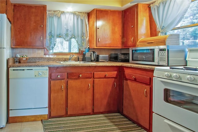 kitchen with decorative backsplash, light tile patterned floors, white appliances, and sink