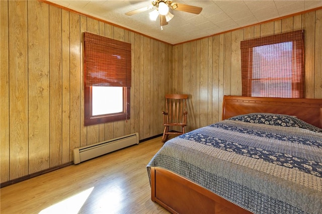 bedroom featuring ceiling fan, wood walls, light wood-type flooring, and a baseboard radiator