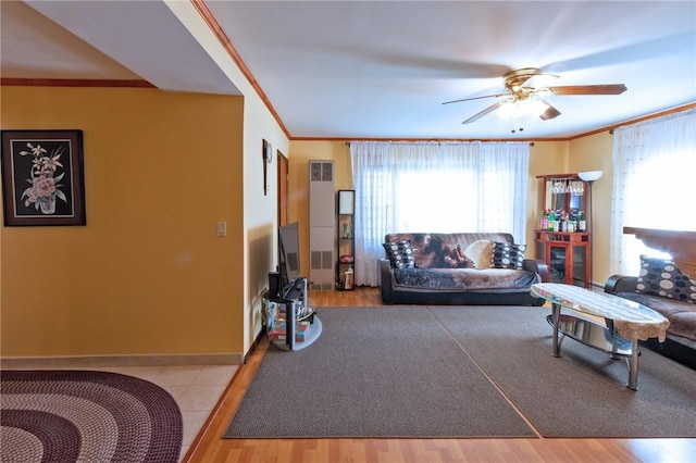 living room featuring ceiling fan, ornamental molding, and light hardwood / wood-style flooring