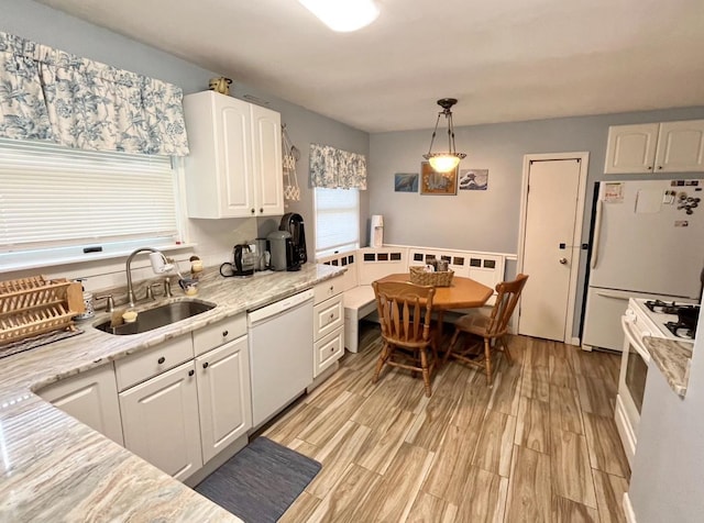 kitchen featuring decorative light fixtures, sink, white appliances, white cabinets, and light stone counters