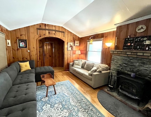 living room with lofted ceiling, a wood stove, and light hardwood / wood-style floors