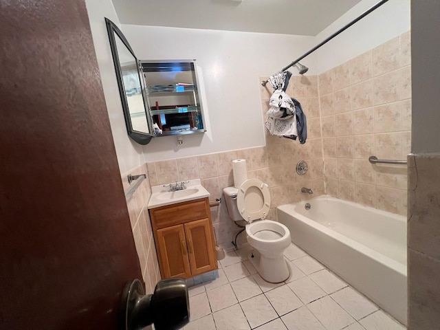 full bathroom with tile patterned floors, vanity, tiled shower / bath combo, tile walls, and toilet