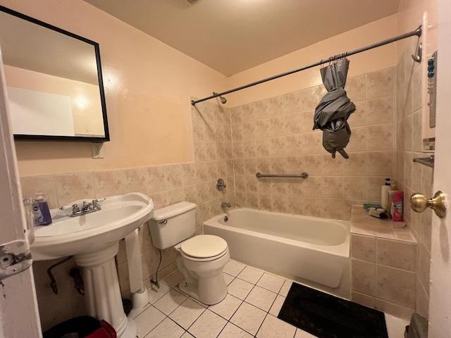 bathroom with tile patterned floors, toilet, tile walls, and tiled shower / bath