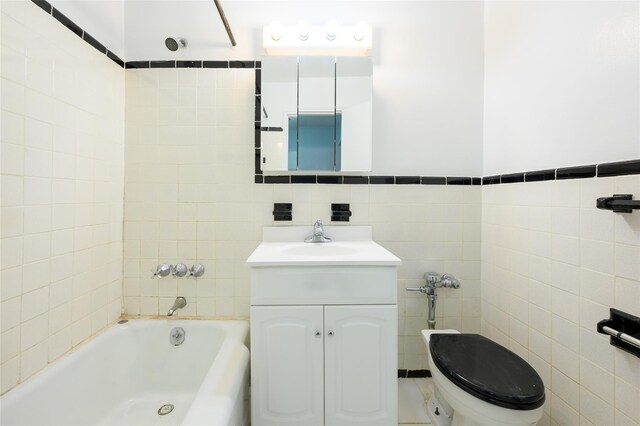 bathroom featuring vanity, tile walls, and toilet