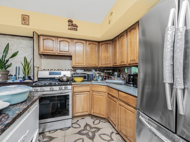 kitchen with decorative backsplash, light tile patterned floors, stainless steel appliances, and dark stone counters