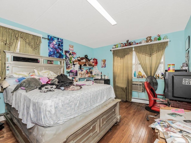 bedroom featuring cooling unit, dark hardwood / wood-style floors, and a baseboard heating unit