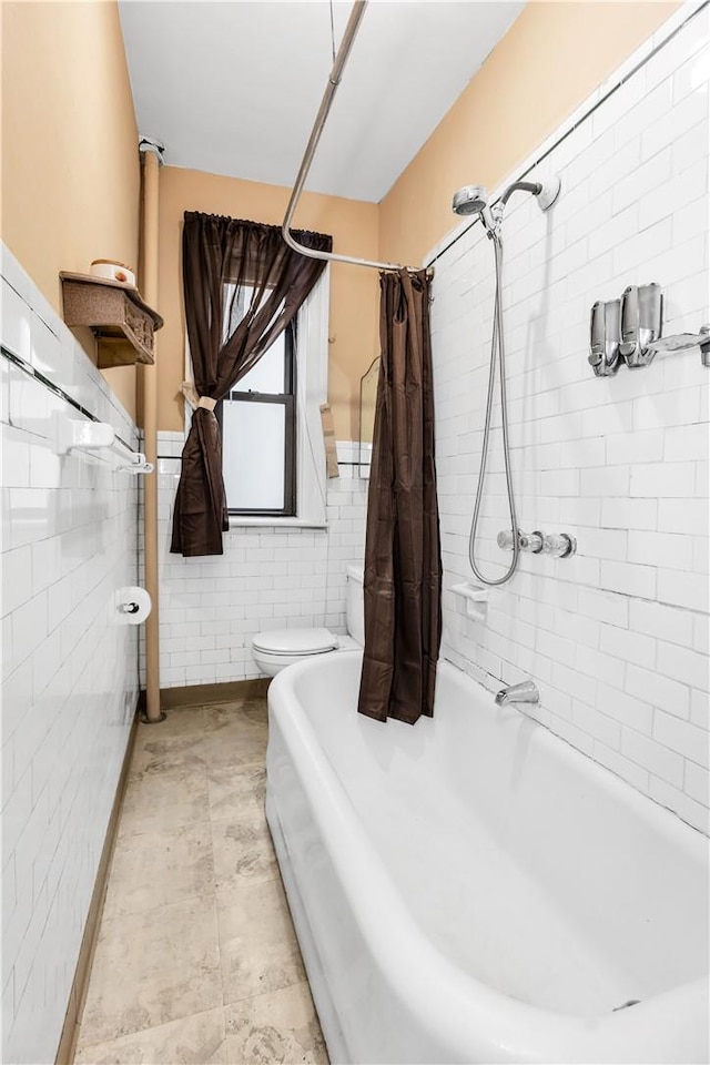 bathroom featuring shower / bath combo, toilet, and tile walls