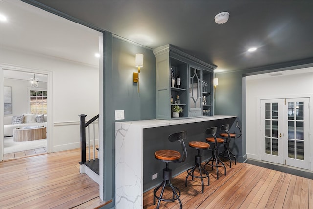 bar with ornamental molding and light wood-type flooring