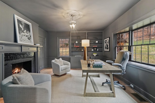 office area with ornamental molding, light hardwood / wood-style flooring, and a healthy amount of sunlight