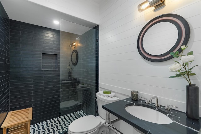 bathroom with tiled shower, toilet, and sink