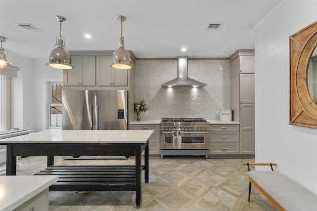 kitchen featuring appliances with stainless steel finishes, gray cabinetry, pendant lighting, and wall chimney range hood