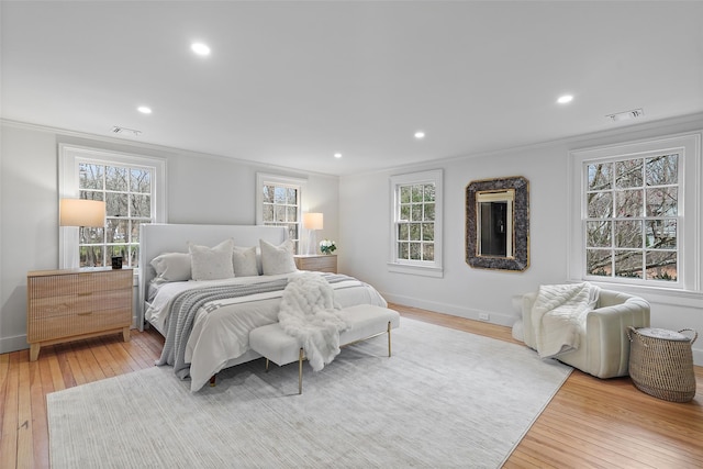 bedroom featuring hardwood / wood-style floors, multiple windows, and ornamental molding