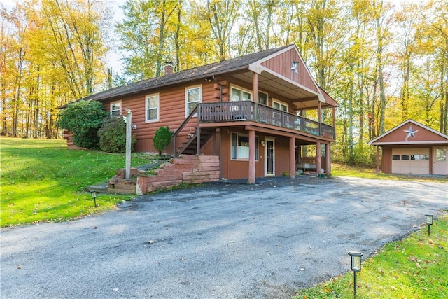 view of front of property featuring a wooden deck, an outbuilding, a front yard, and a garage