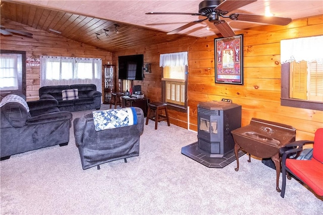 carpeted living room featuring wooden walls, vaulted ceiling, a wood stove, and wooden ceiling