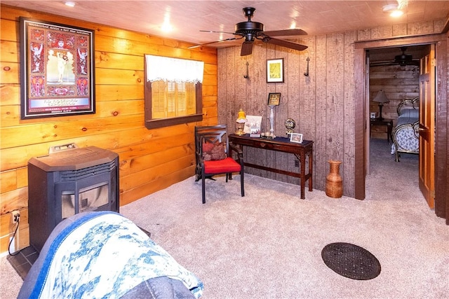 sitting room with carpet, ceiling fan, and wooden walls