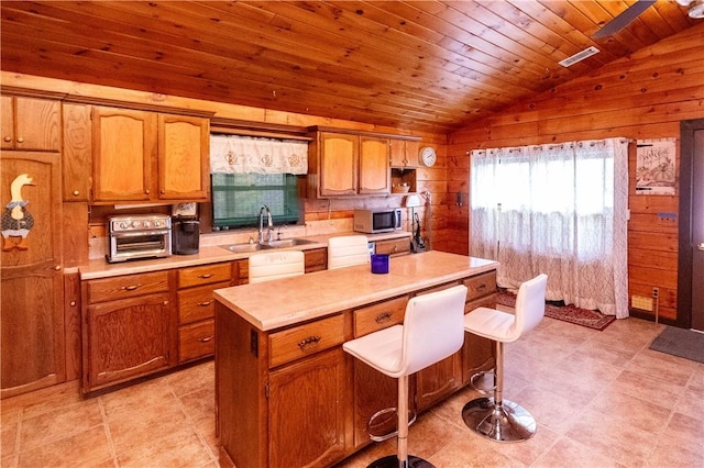 kitchen featuring sink, wooden ceiling, a center island, lofted ceiling, and wood walls