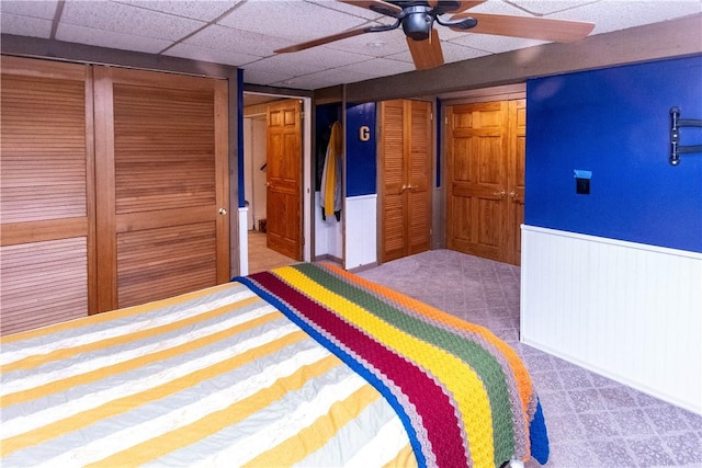 unfurnished bedroom featuring a paneled ceiling, carpet floors, ceiling fan, and wooden walls