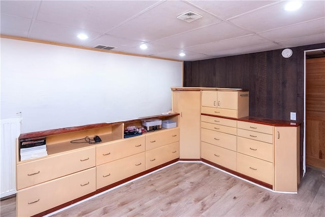 interior space with wood walls, light hardwood / wood-style floors, and cream cabinetry