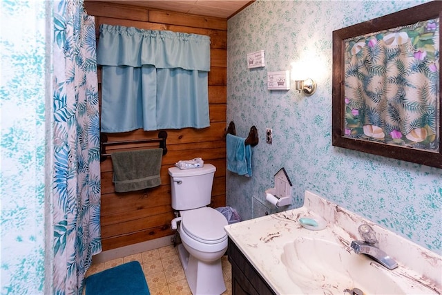 bathroom featuring vanity, wood walls, and toilet