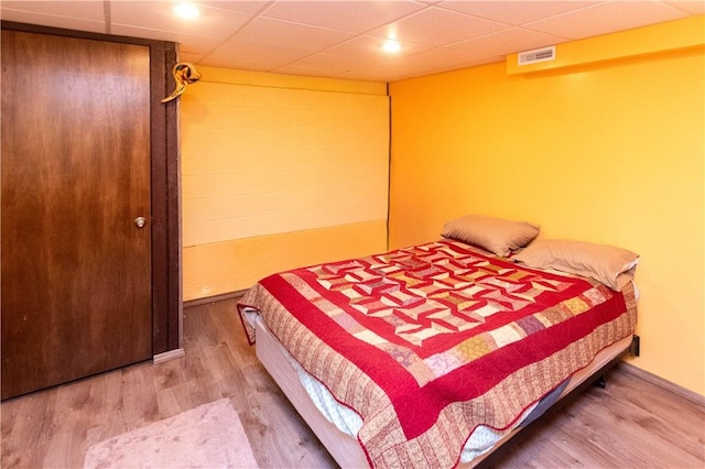 bedroom with a paneled ceiling and hardwood / wood-style floors