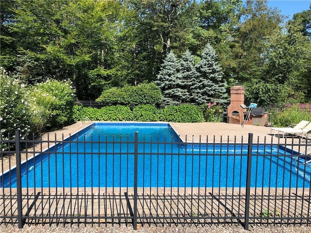 view of pool with an outdoor brick fireplace and a patio area