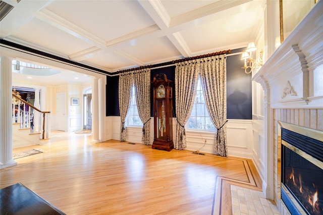 living room featuring light hardwood / wood-style floors, ornamental molding, beam ceiling, and coffered ceiling