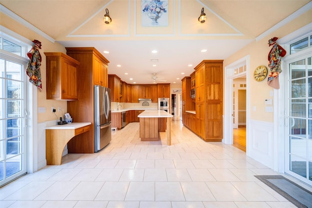 kitchen featuring a kitchen breakfast bar, ceiling fan, ornamental molding, appliances with stainless steel finishes, and a kitchen island