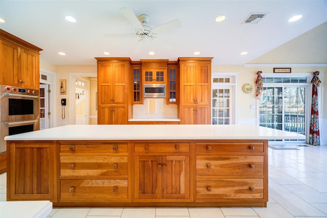 kitchen with ceiling fan, a center island, light tile patterned floors, and stainless steel appliances