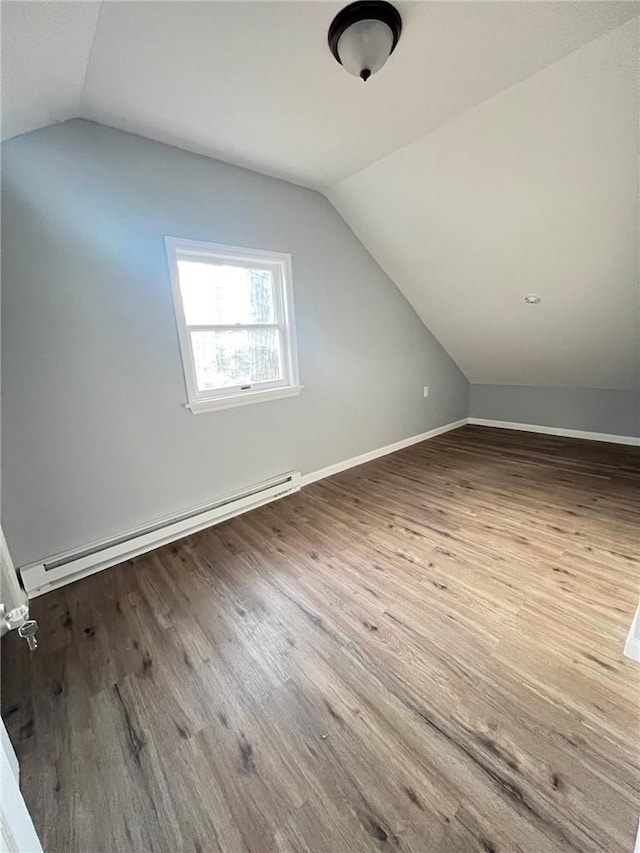 additional living space featuring hardwood / wood-style floors, a baseboard radiator, and lofted ceiling