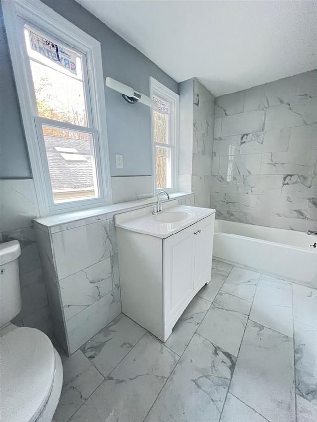 full bathroom featuring vanity, a healthy amount of sunlight, tiled shower / bath combo, and toilet