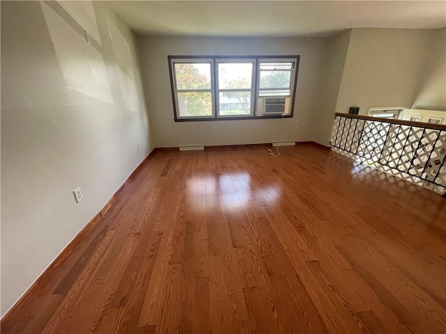 unfurnished room featuring cooling unit, wood-type flooring, and a baseboard heating unit