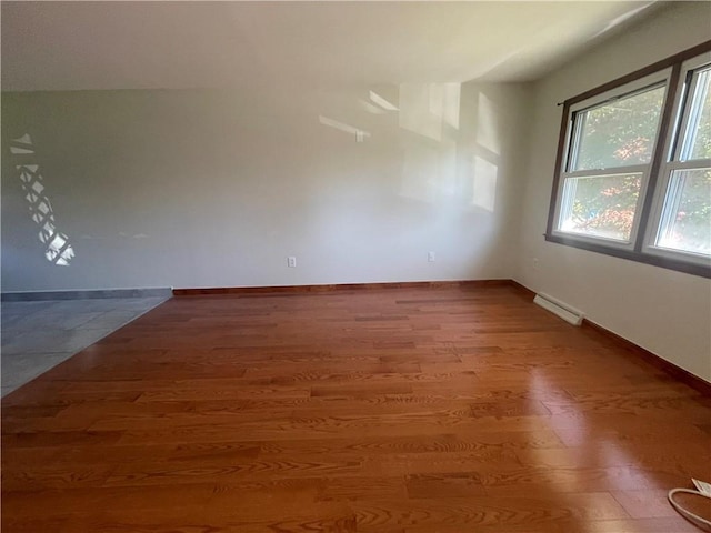 unfurnished room featuring baseboard heating and wood-type flooring